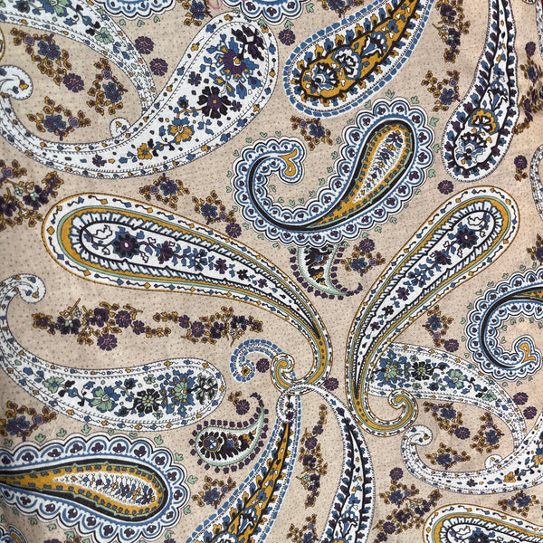 Close-up of a patterned fabric with paisley design on a beige background 100% cotton