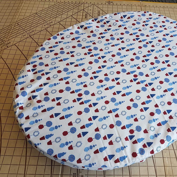 Round fabric cover with red, white, and blue pattern on a cutting mat